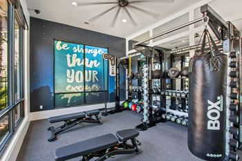 A gym room with a punching bag and weights.